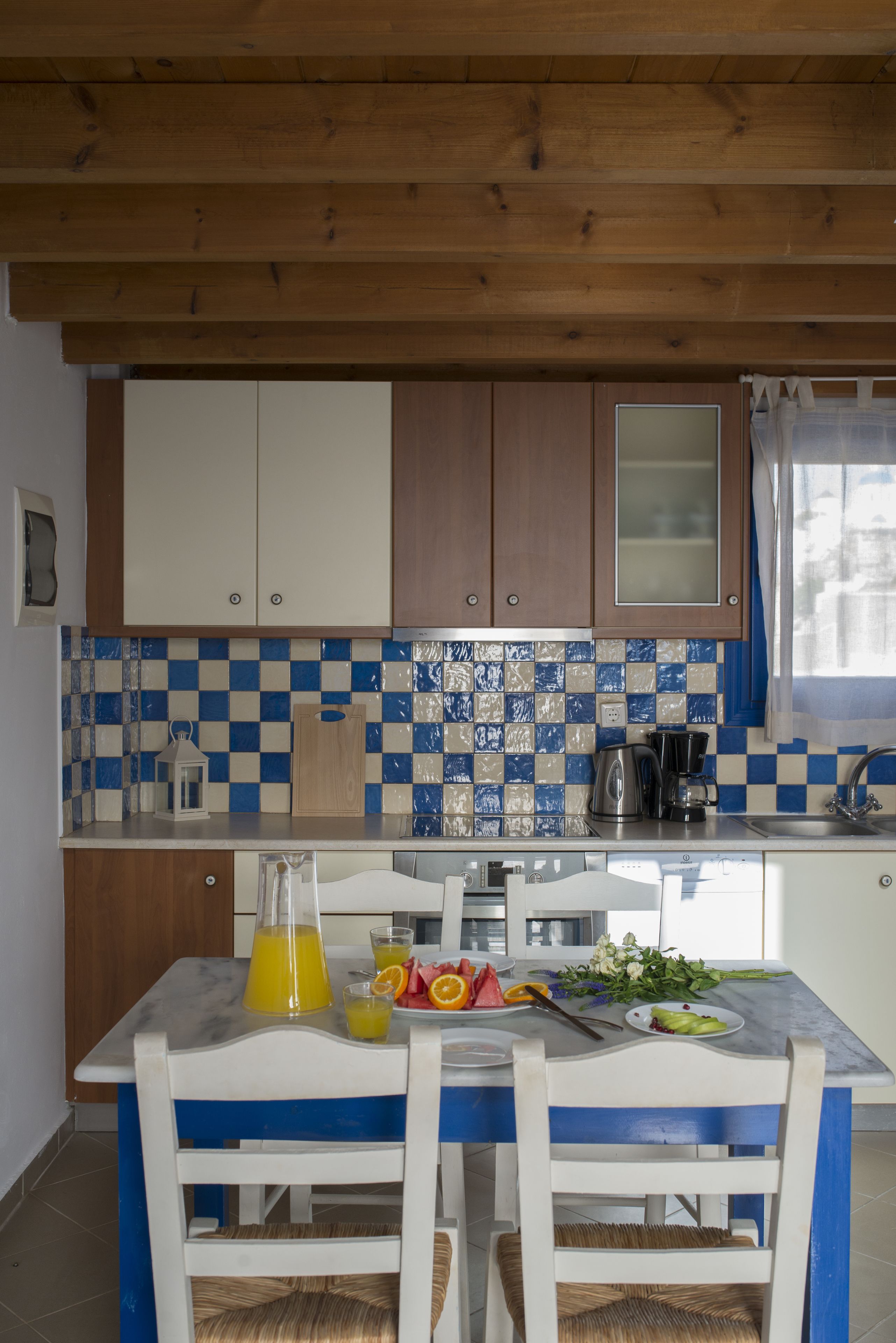 Una cucina con mobili impiallacciati in legno, zoccolo di piastrelle e tavolo da pranzo con sedie.