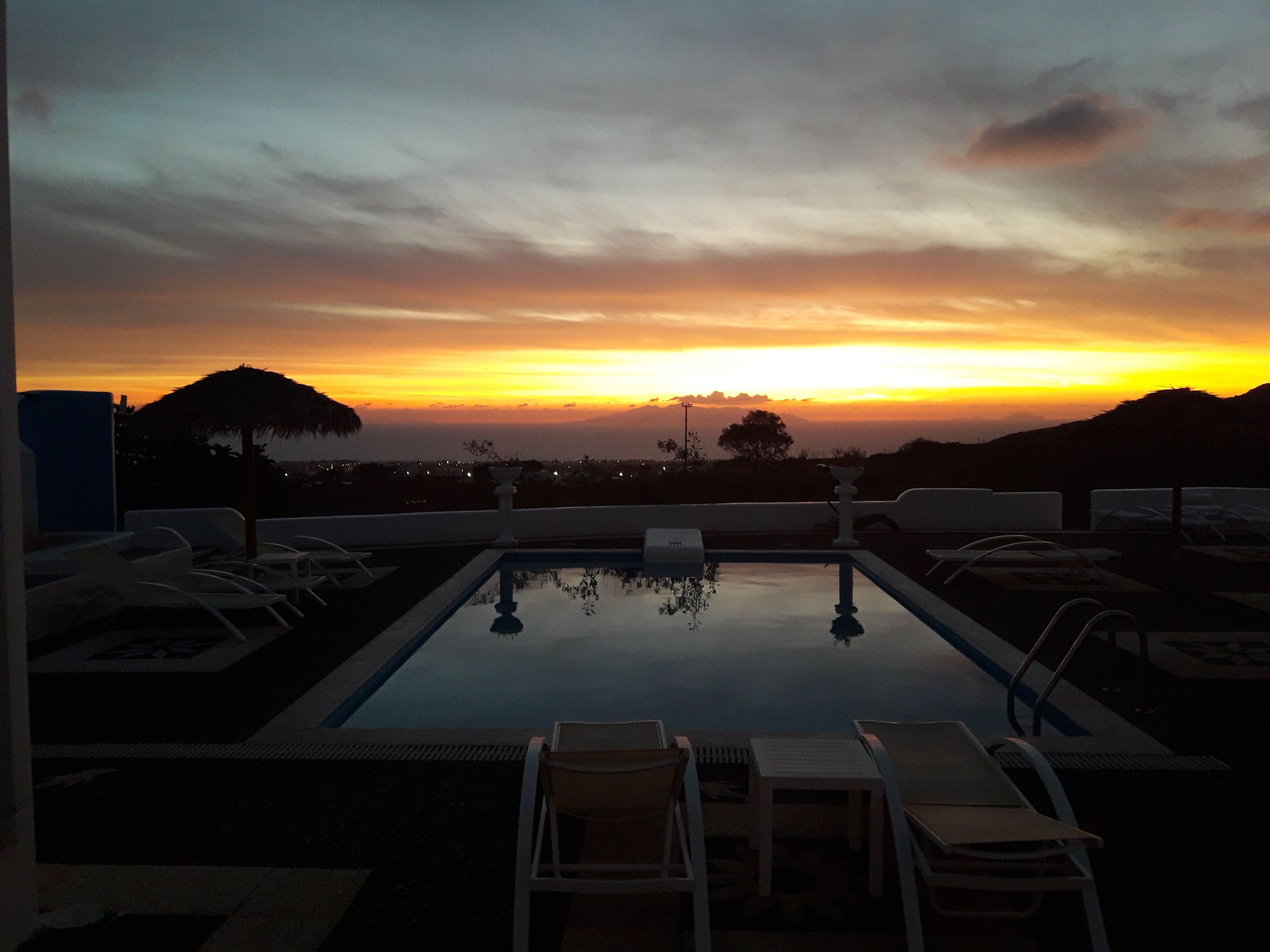Ein Poolbereich mit Liegestühlen und Blick auf einen Sonnenuntergang.