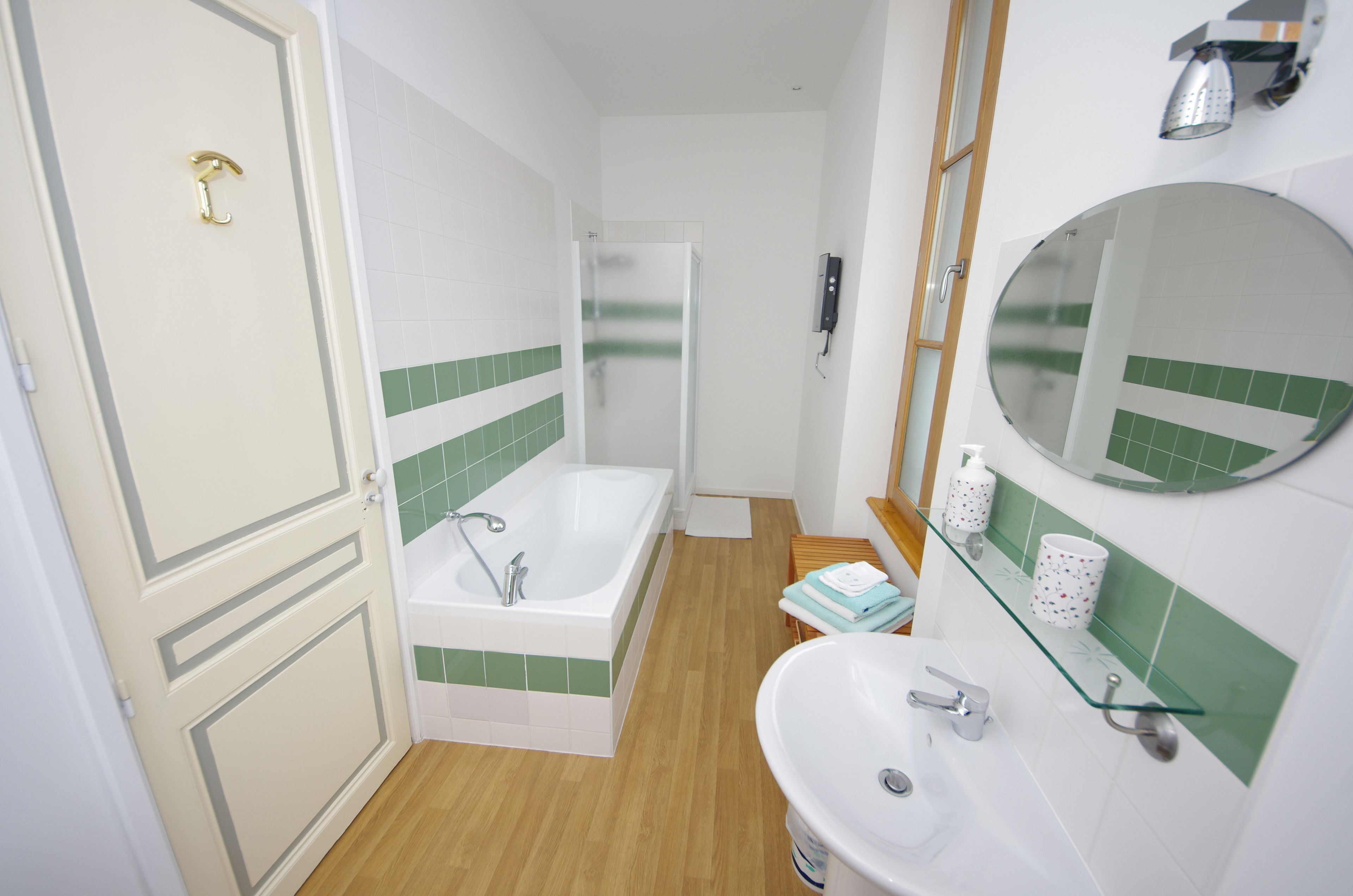 A bathroom with a bathtub, a sink, a mirror, and a shower.