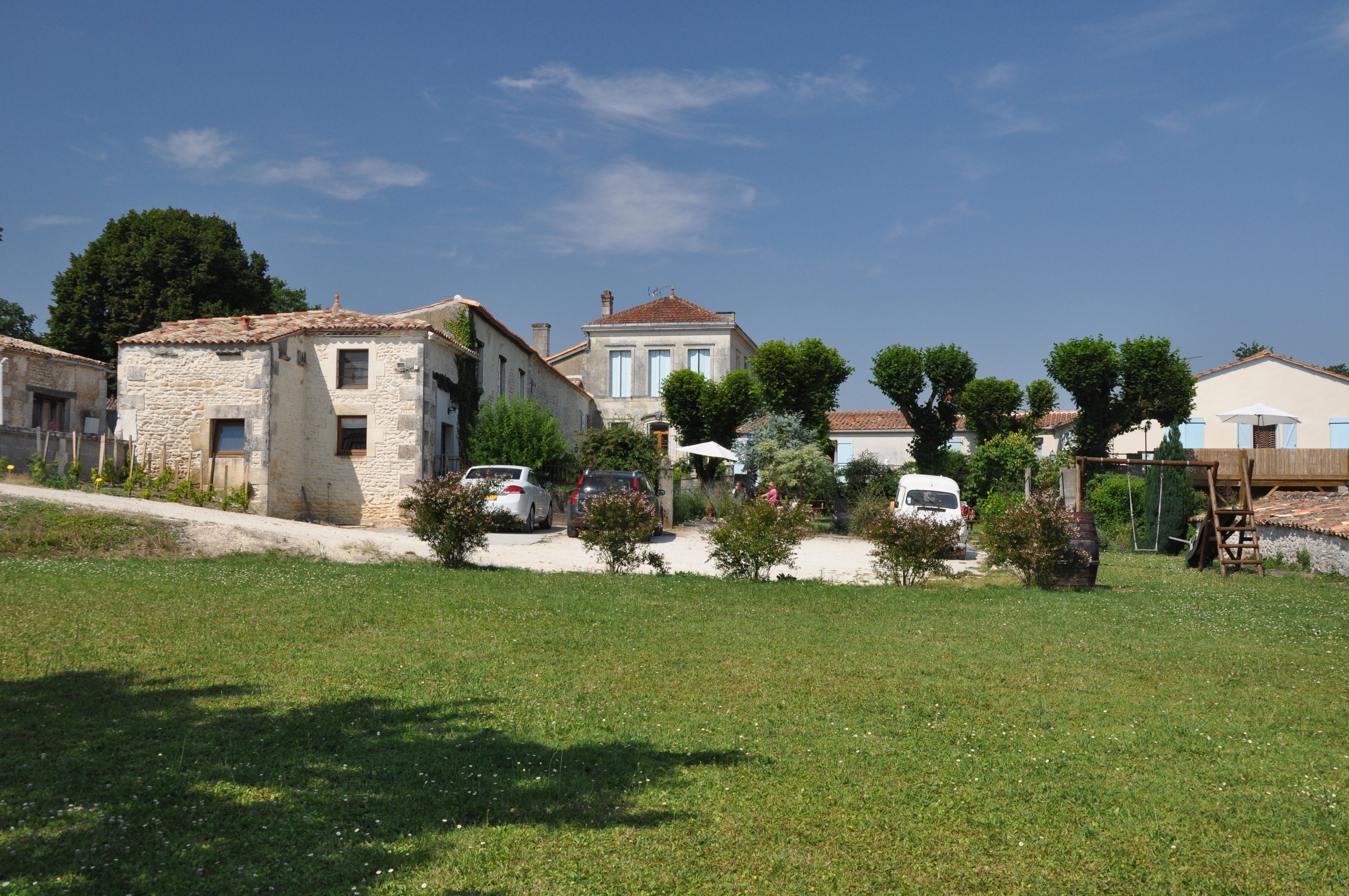 A residential area with stone buildings, a grassy field, and parked cars.
