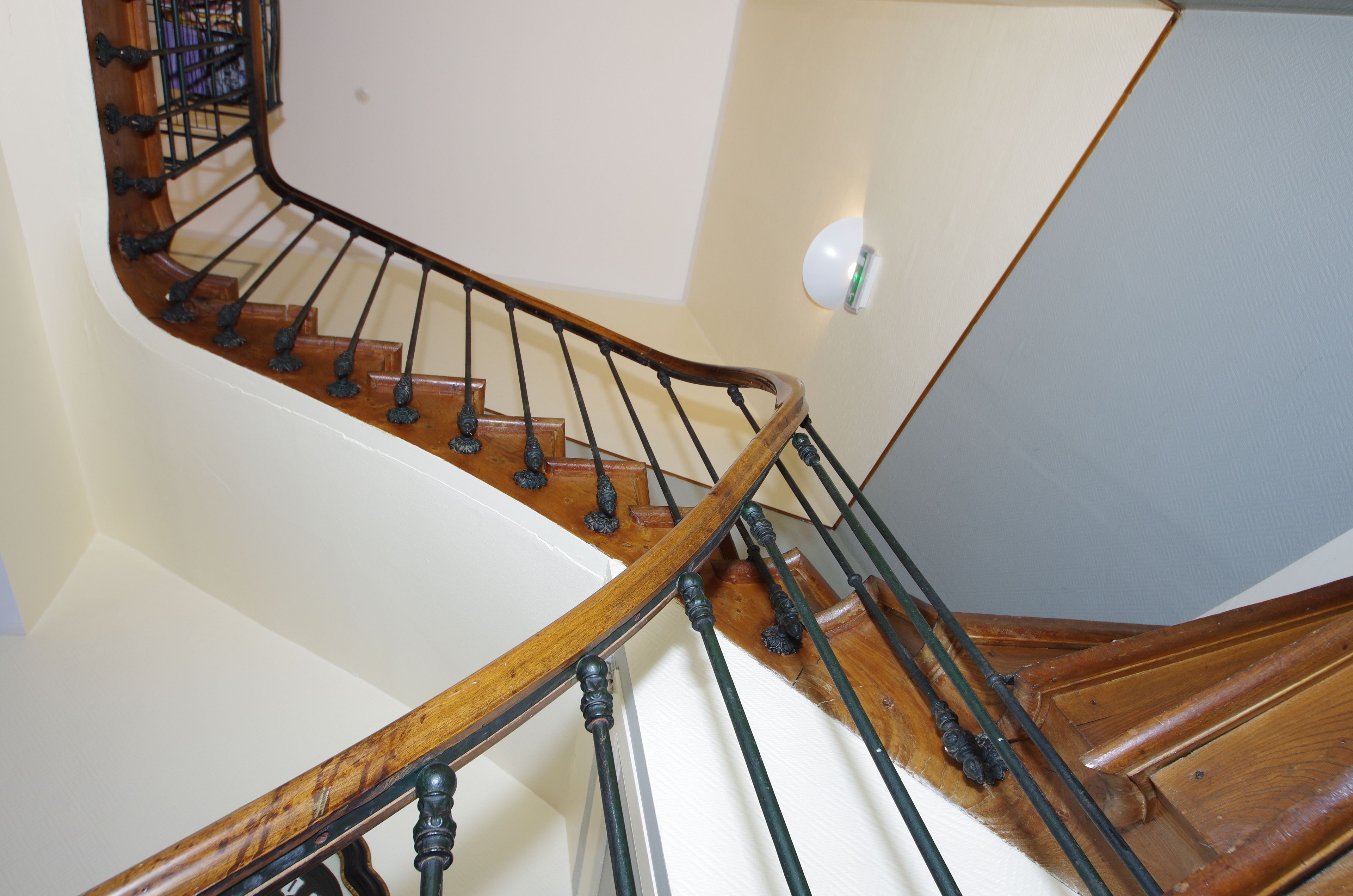 Una escalera de madera con balaustres negros y una pared blanca.