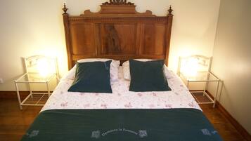 Een bed met een houten hoofdbord, twee nachtkastjes en een bloemenbedekking.