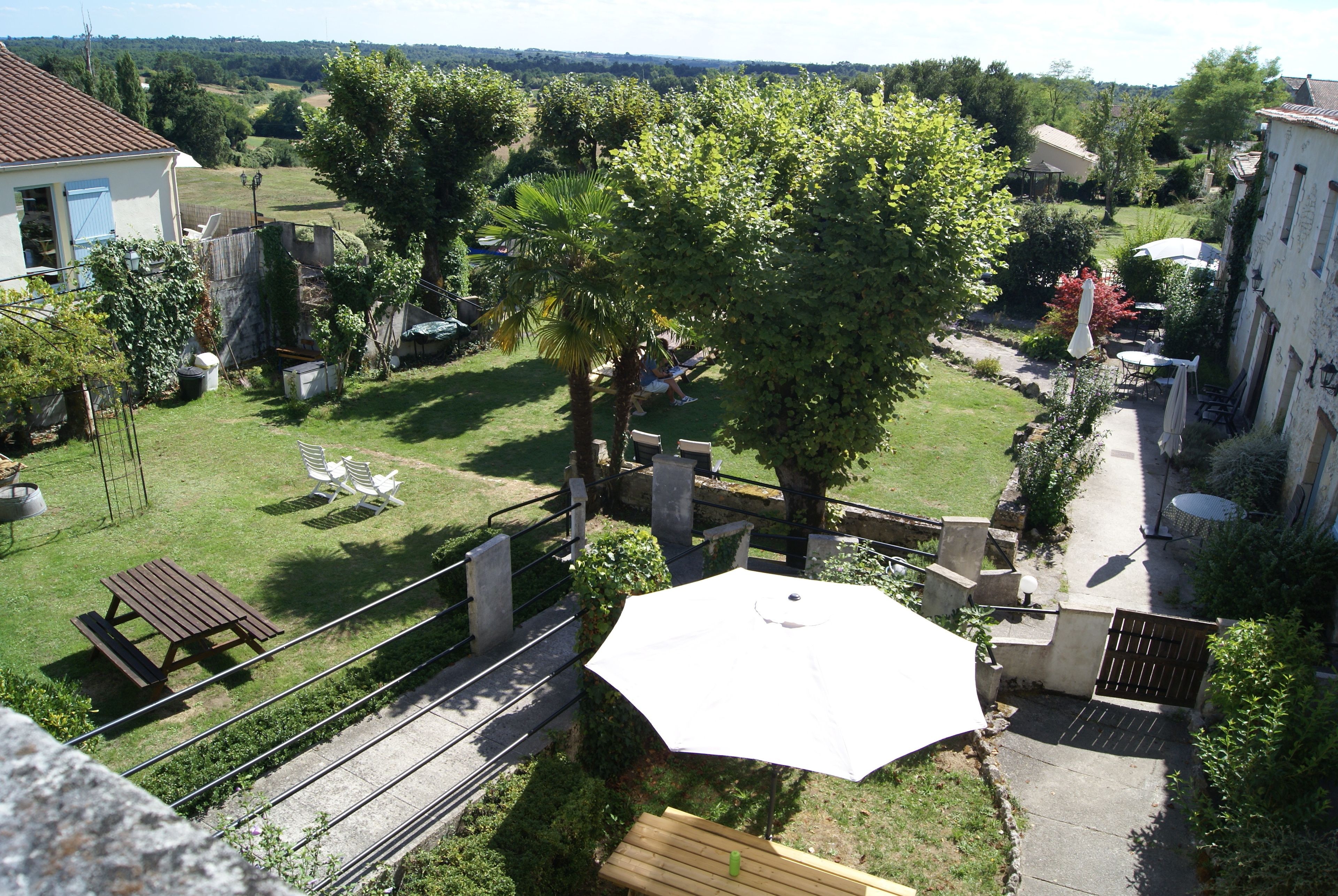 A residential backyard with a patio area, a large umbrella, and a wooden bench.