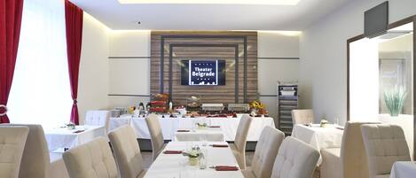 A hotel dining area with a long table set for a banquet, a buffet in the background, and a sign for 'Hotel Belgrade'.