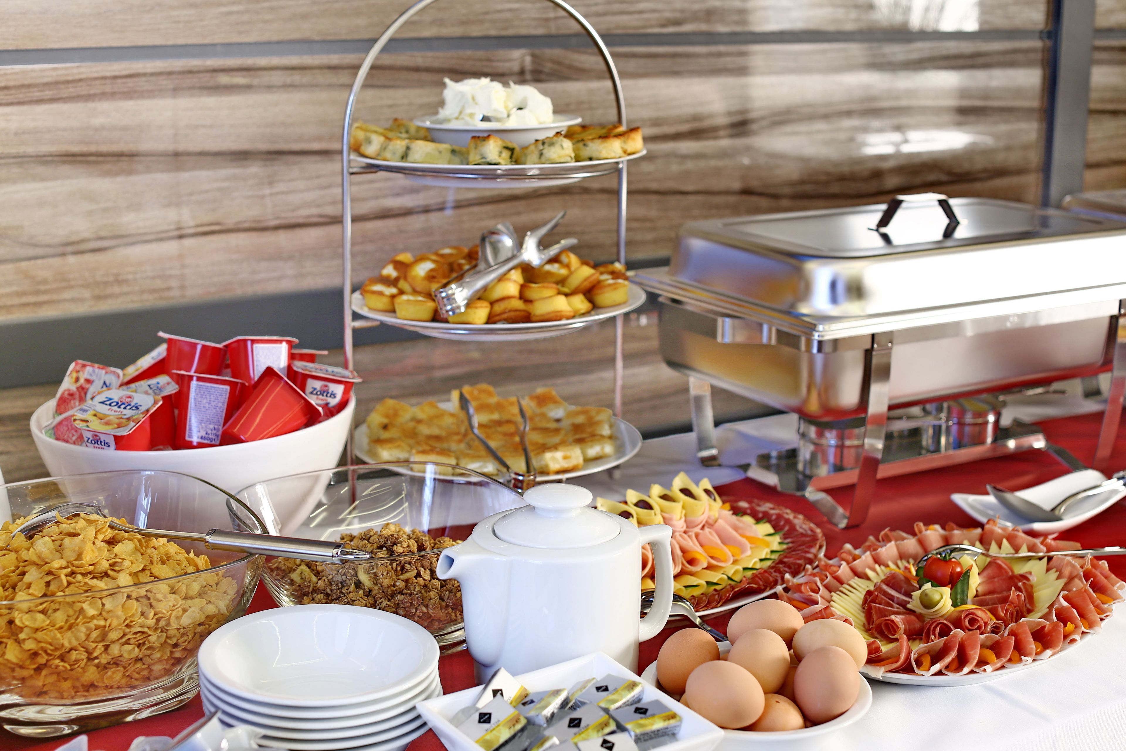 A buffet with various food items including cereal, eggs, and meats.