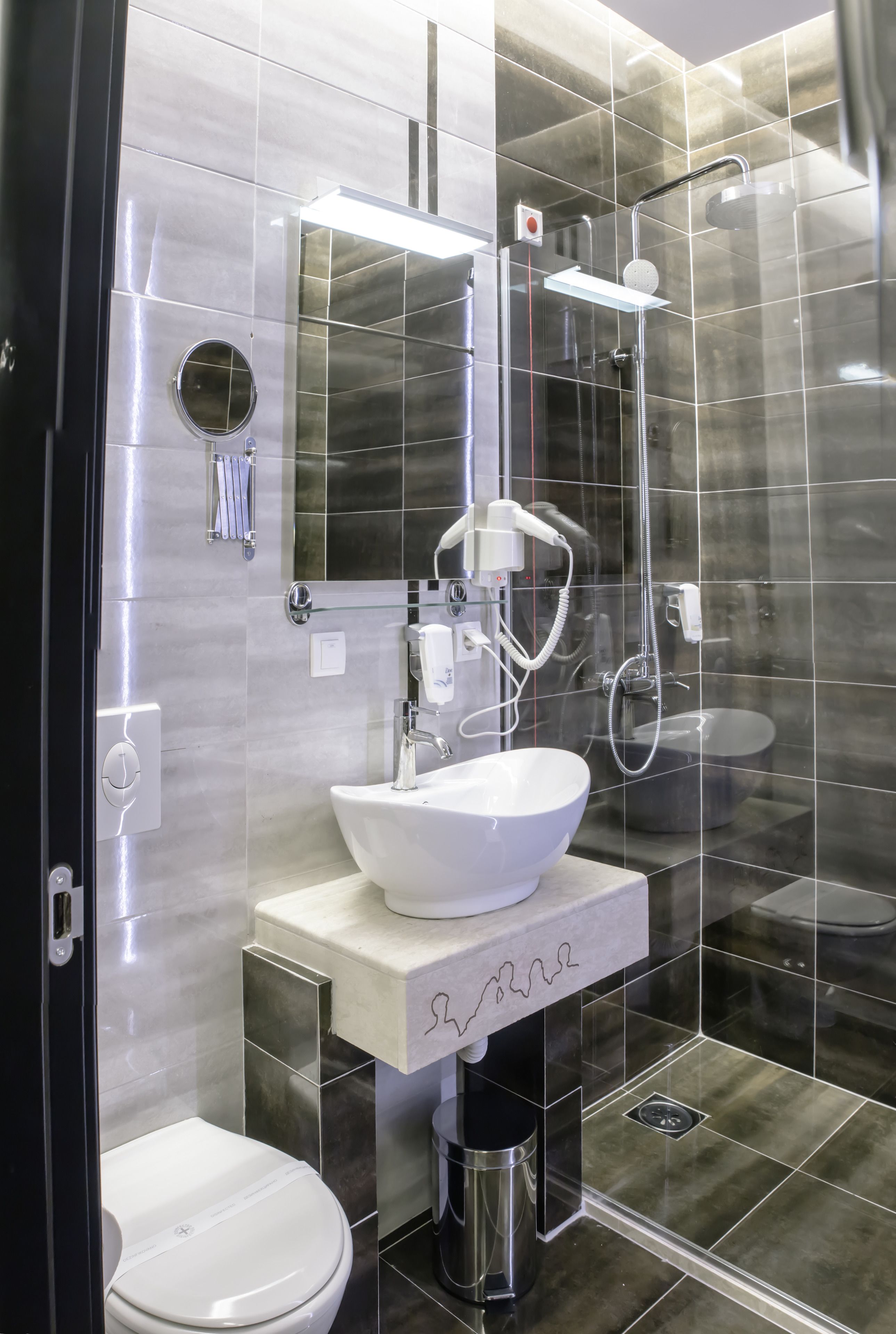 Un baño moderno con ducha de vidrio, un lavamanos blanco y un inodoro.
