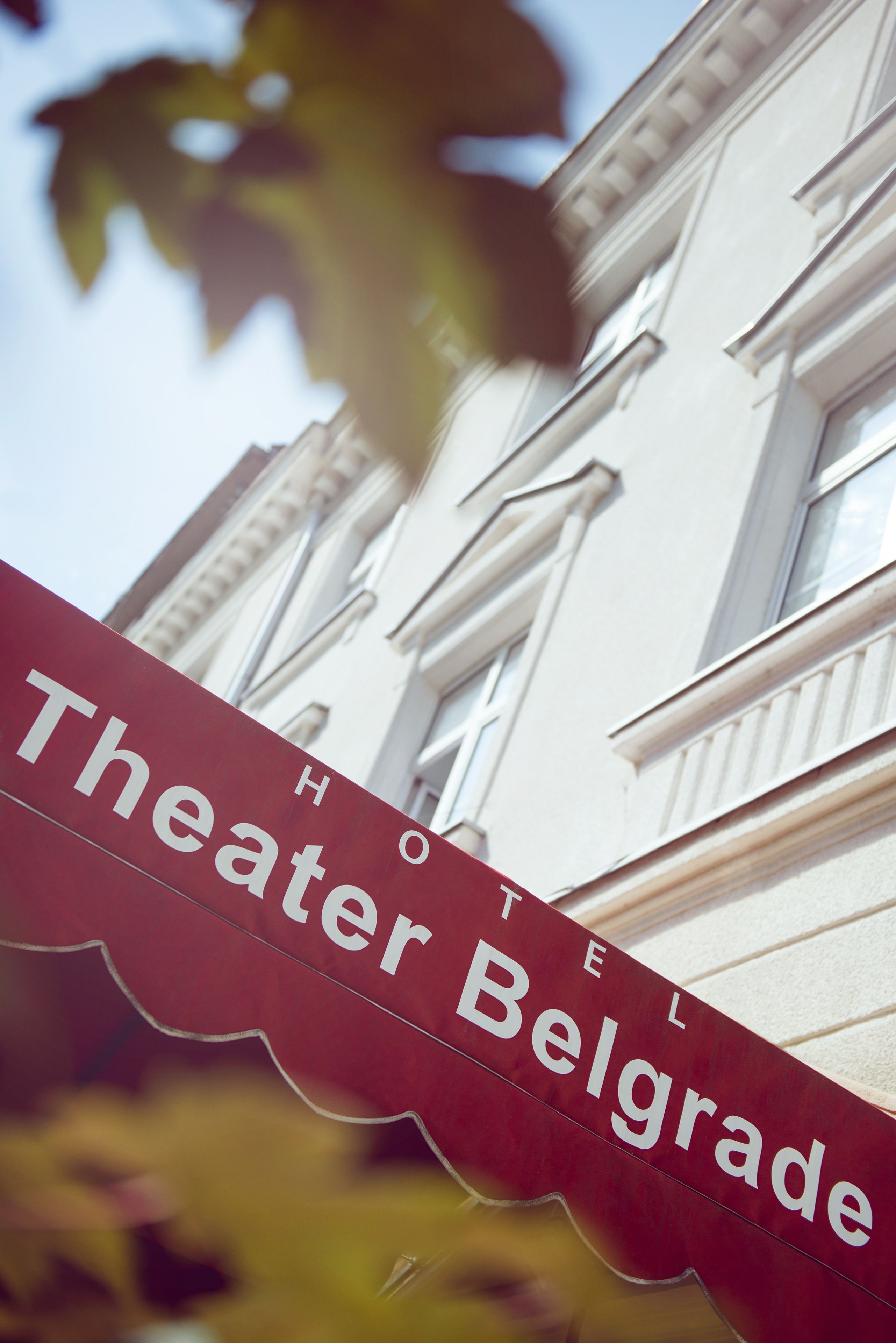 A hotel sign with the name "Theater Belgrade" in a red banner.