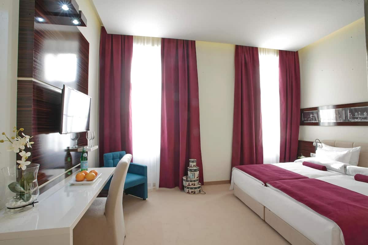 A hotel room with a bed, a desk with a chair, a TV, and a decorative item.
