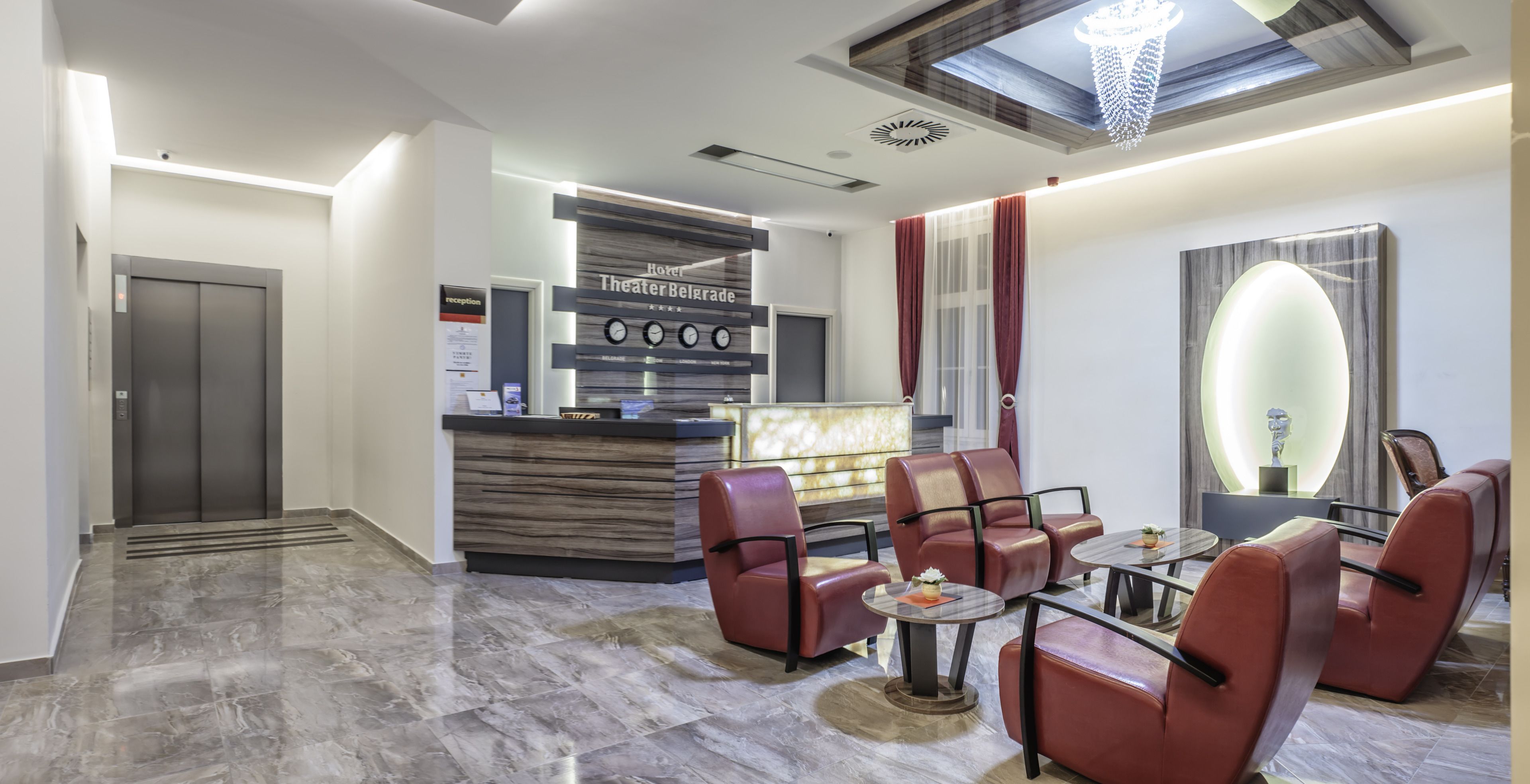 Un hall d’hôtel comprenant un comptoir d’accueil, un espace salon et un lustre moderne.