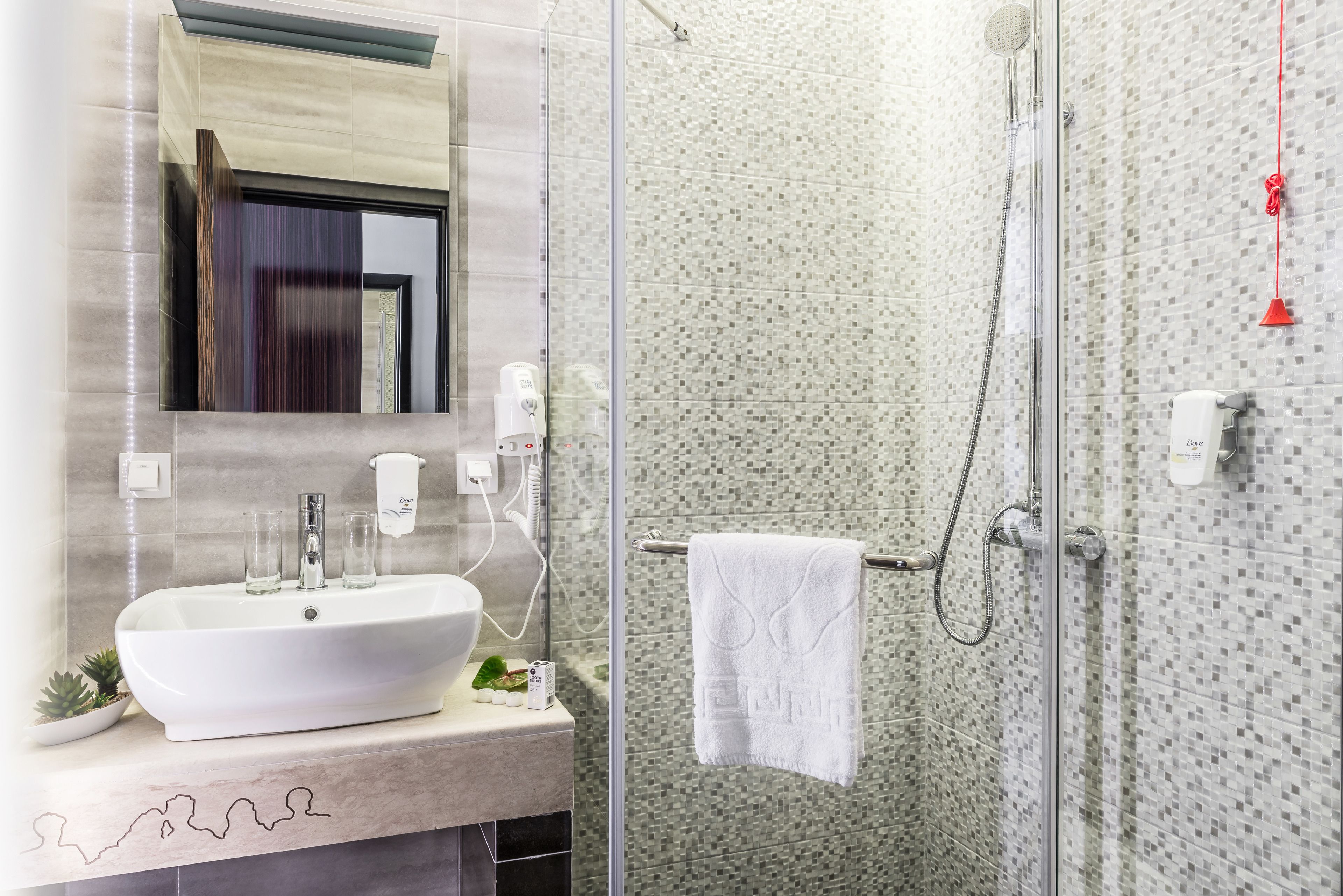 A bathroom with a large sink, a mirror, a shower with a glass door, and a towel hanging on a rack.