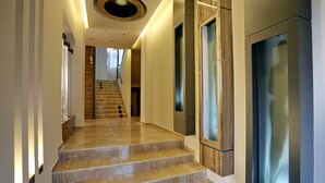 Una escalera moderna con detalles de madera y paneles de vidrio, que conduce a un segundo piso.