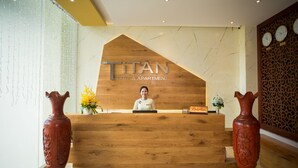 Un mostrador de recepción con detalles de madera y un cartel que dice "TITAN HOTEL & APARTMENT".