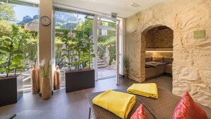 Un moderno espacio de spa con una pared de piedra, un sofá y una toalla amarilla en el suelo.