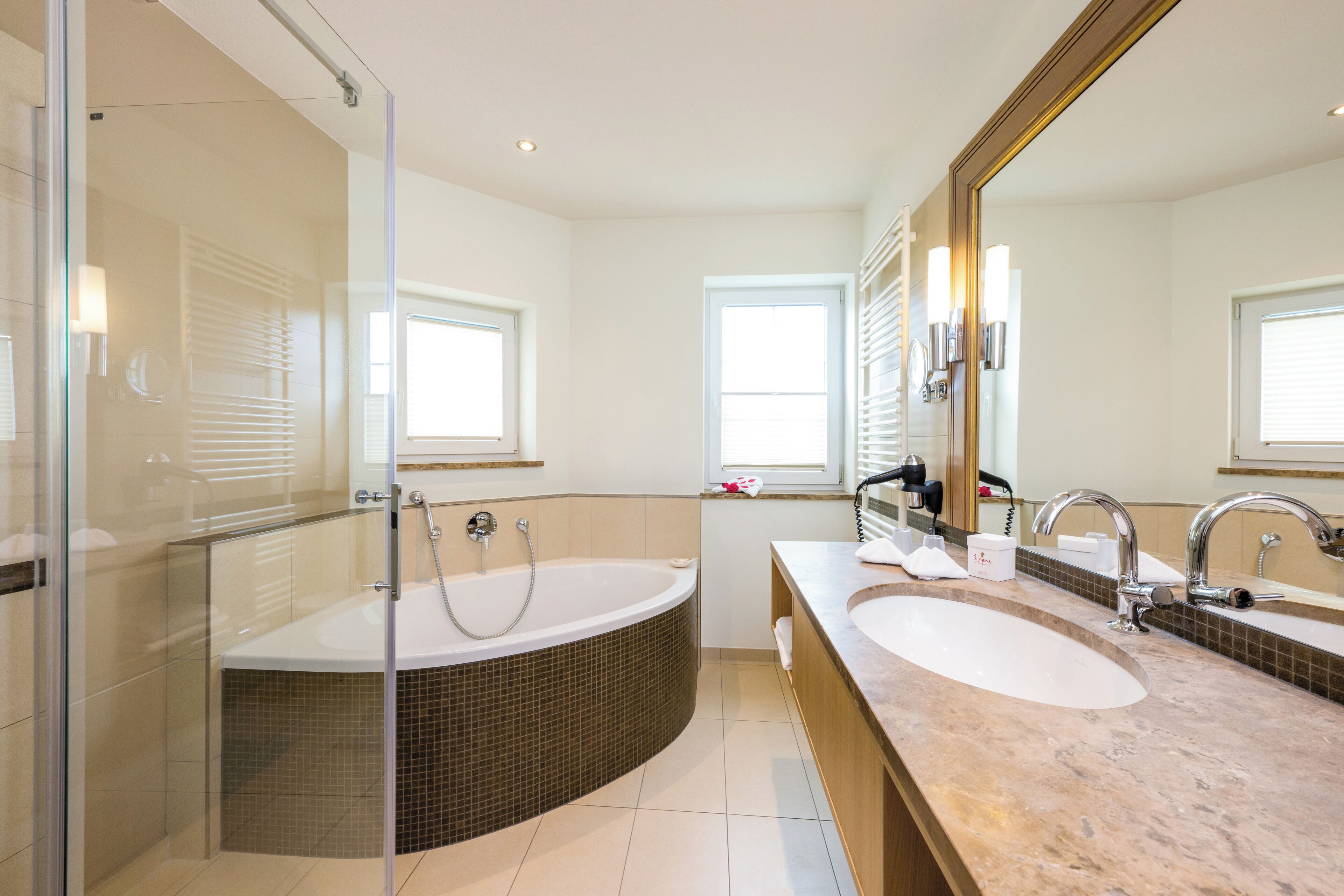 A modern bathroom with a glass-enclosed shower, a freestanding bathtub, and a double sink vanity.