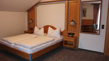 Cozy bedroom with a wooden bed, patterned carpet, and a wardrobe with mirror.