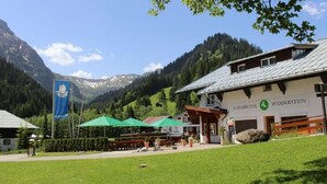 A hotel with a mountain backdrop, outdoor seating, and a clear sky. - Alpenhotel Widderstein (Mittelberg)
