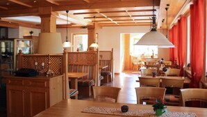 A wooden interior with a dining area, wooden furniture, and a large window. - Alpenhotel Widderstein (Mittelberg)