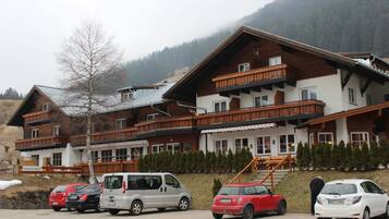 Un hotel con diversi balconi, una seggiovia e un'area di parcheggio con diverse automobili.
