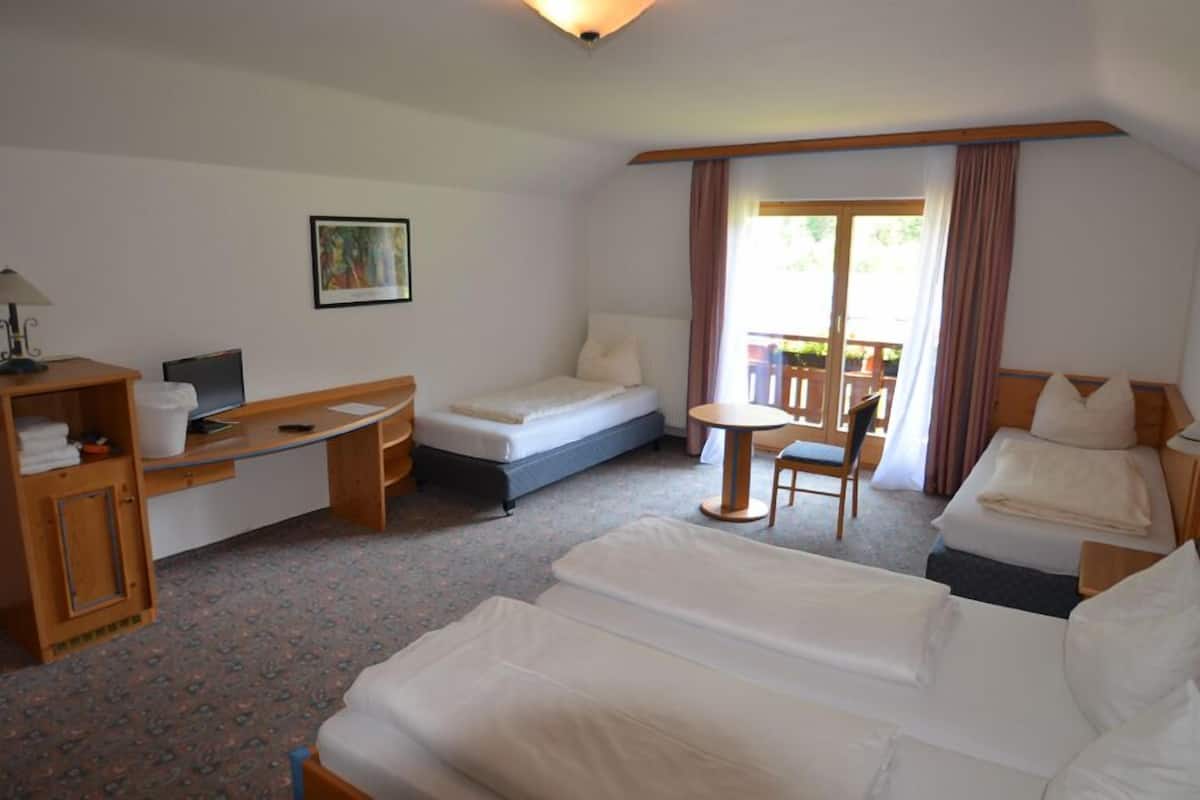 A hotel room with a bed, a desk, a chair, and a small table.