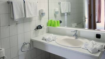 Une salle de bain avec un lavabo blanc, un miroir et deux serviettes blanches suspendues à des porte-serviettes.
