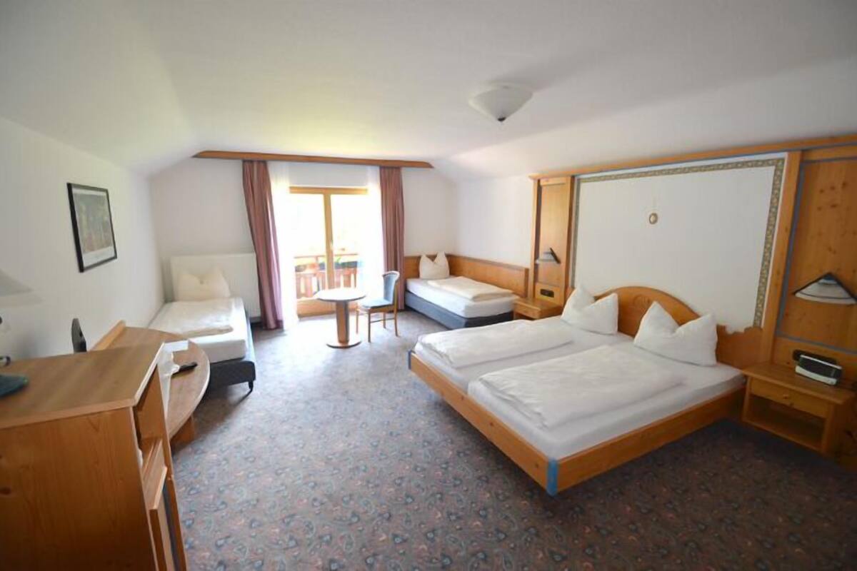 A hotel room with a bed, a desk, a chair, and a small table.
