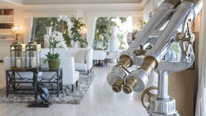 Una habitación con un telescopio, muebles blancos y plantas decorativas.