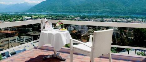 Una terraza con una mesa y una silla, con vistas a un paisaje montañoso y un lago.