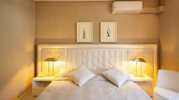 A neatly arranged bedroom with a large bed, two bedside tables with lamps, a headboard, and two framed artworks on the wall.