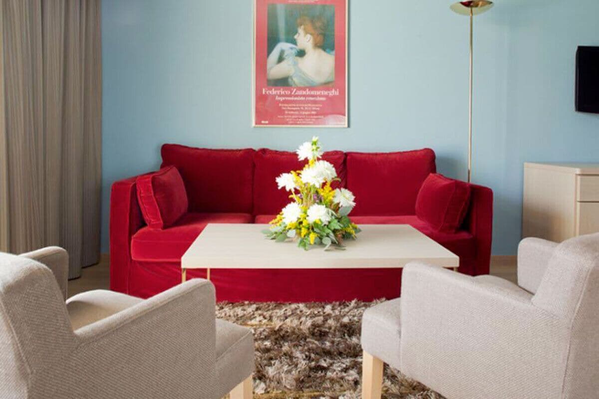 Ein Wohnzimmer mit einem roten Sofa, einem weißen Couchtisch und einer floralen Tischdekoration.
