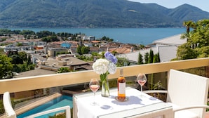 Un balcón con una mesa preparada para dos, con vistas a un lago y montañas.