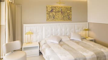 A modern bedroom with a large bed, two bedside tables with lamps, a chair, and a decorative wall piece.