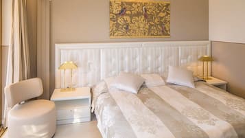 Ein Hotelzimmer mit einem großen Bett, zwei Nachttischen, einem Sessel und einer Wanddekoration.