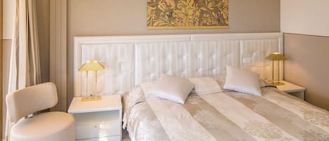 A hotel room with a large bed, two bedside tables, a chair, and a decorative wall piece.