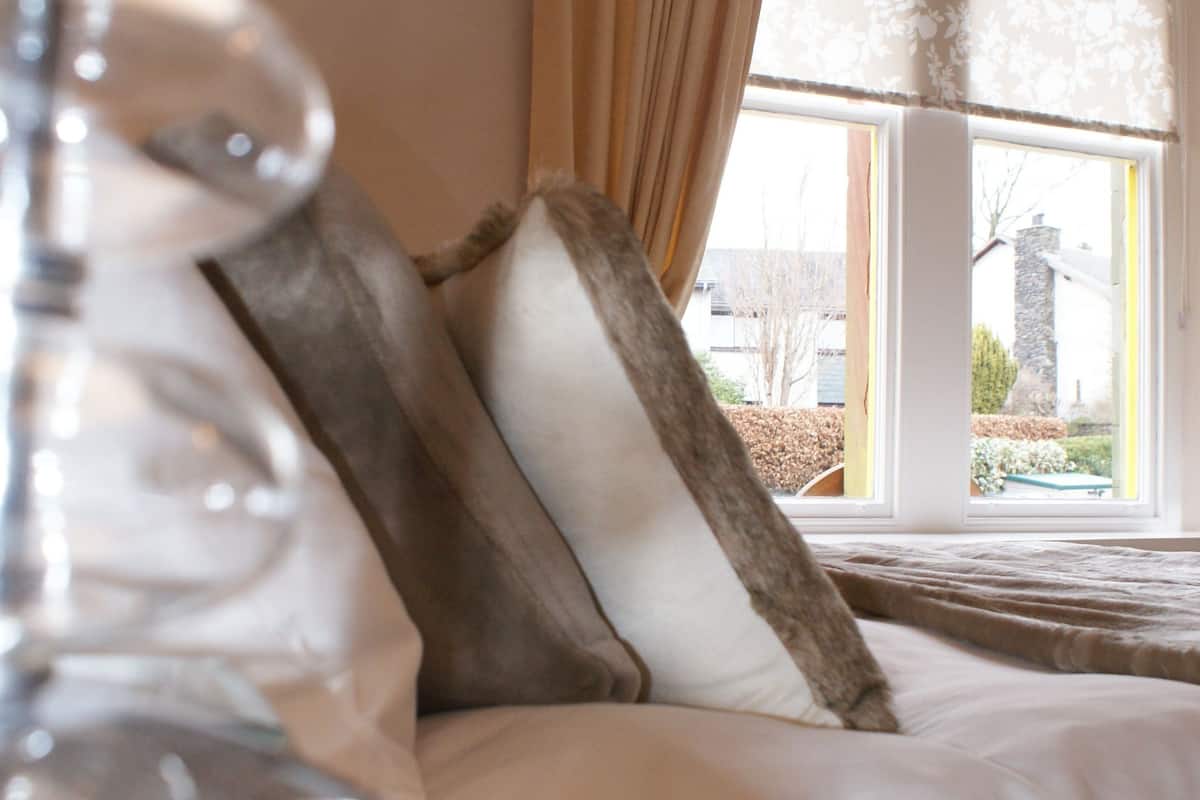 A bedroom with a bed, a window with curtains, and a lamp.