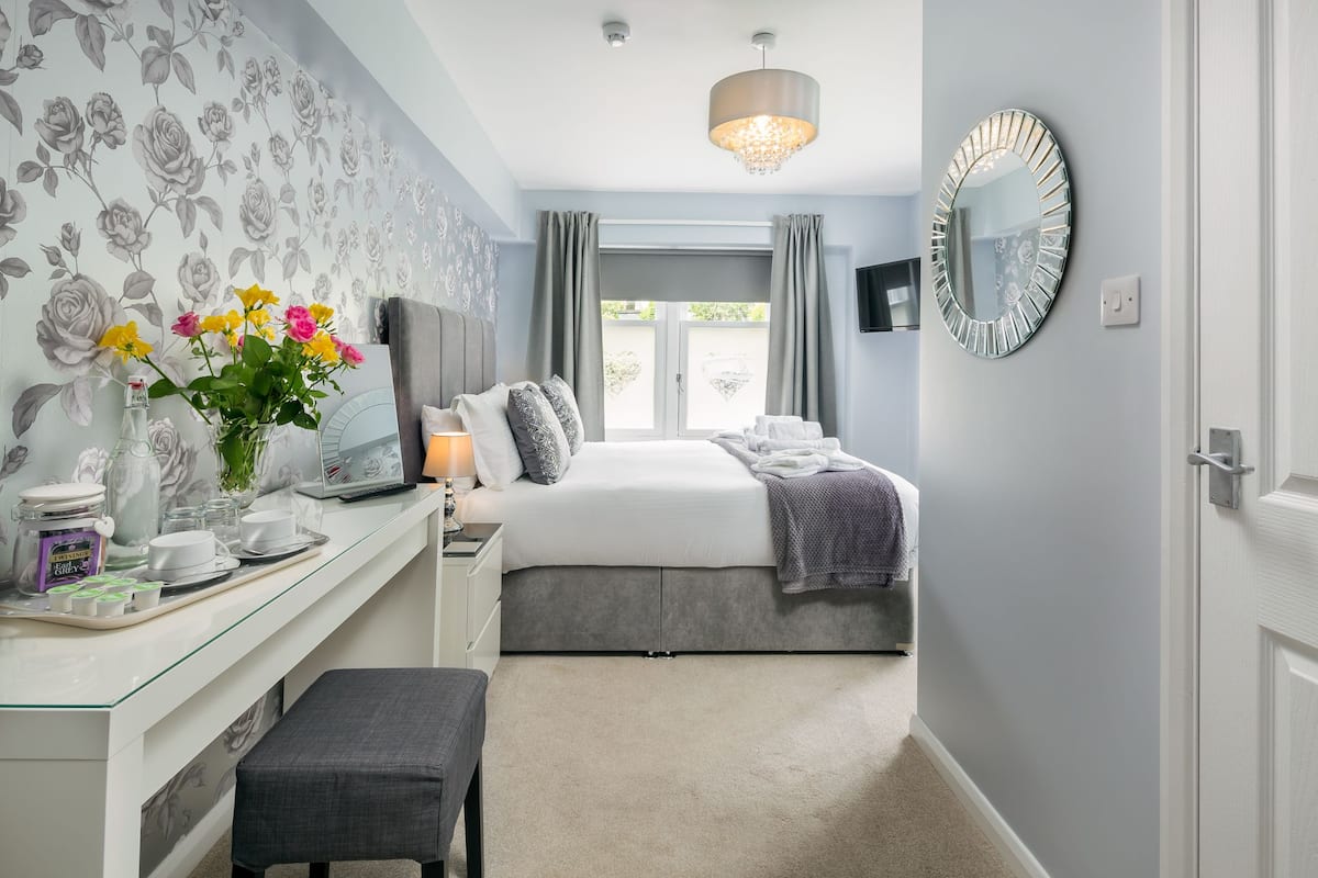 A bedroom with a bed, bedside table, lamp, and a window with curtains.