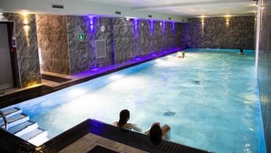 Una piscina interior con pared de mármol y un reloj.