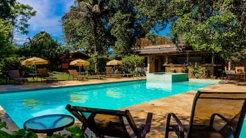 Una piscina al aire libre, sombrillas, sillones reclinables de piscina