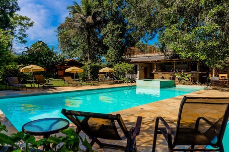 Una piscina al aire libre, sombrillas, sillones reclinables de piscina