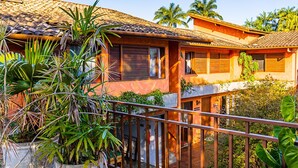 A two-story house with a tiled roof, a balcony with a metal railing, and various potted plants. - Pousada Jamboo (Ubatuba)
