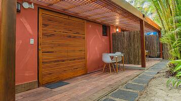 A modern building with a large wooden shutter door, a small table with chairs, and a bamboo fence.