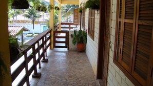 A covered outdoor area with a tiled floor, wooden railings, and potted plants. - Aquarius Chalés (Ubatuba)