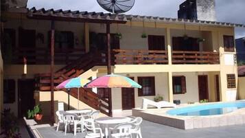 A two-story building with a swimming pool, outdoor seating, and a satellite dish.