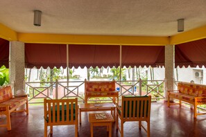 A covered outdoor seating area with wooden furniture and a view of the garden.
