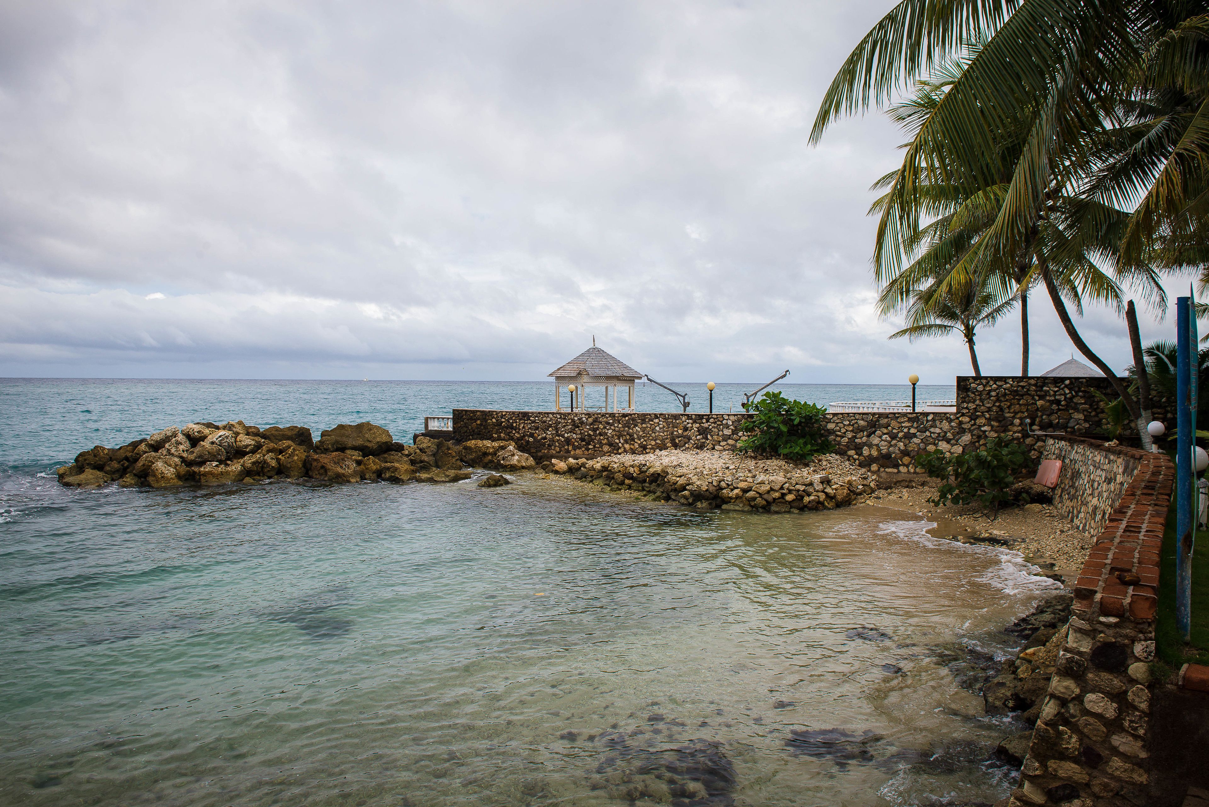 A coastal area with a gazebo, clear water, and a stone wall.