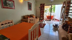 A living room with a dining table, a sofa, and a balcony with outdoor furniture.