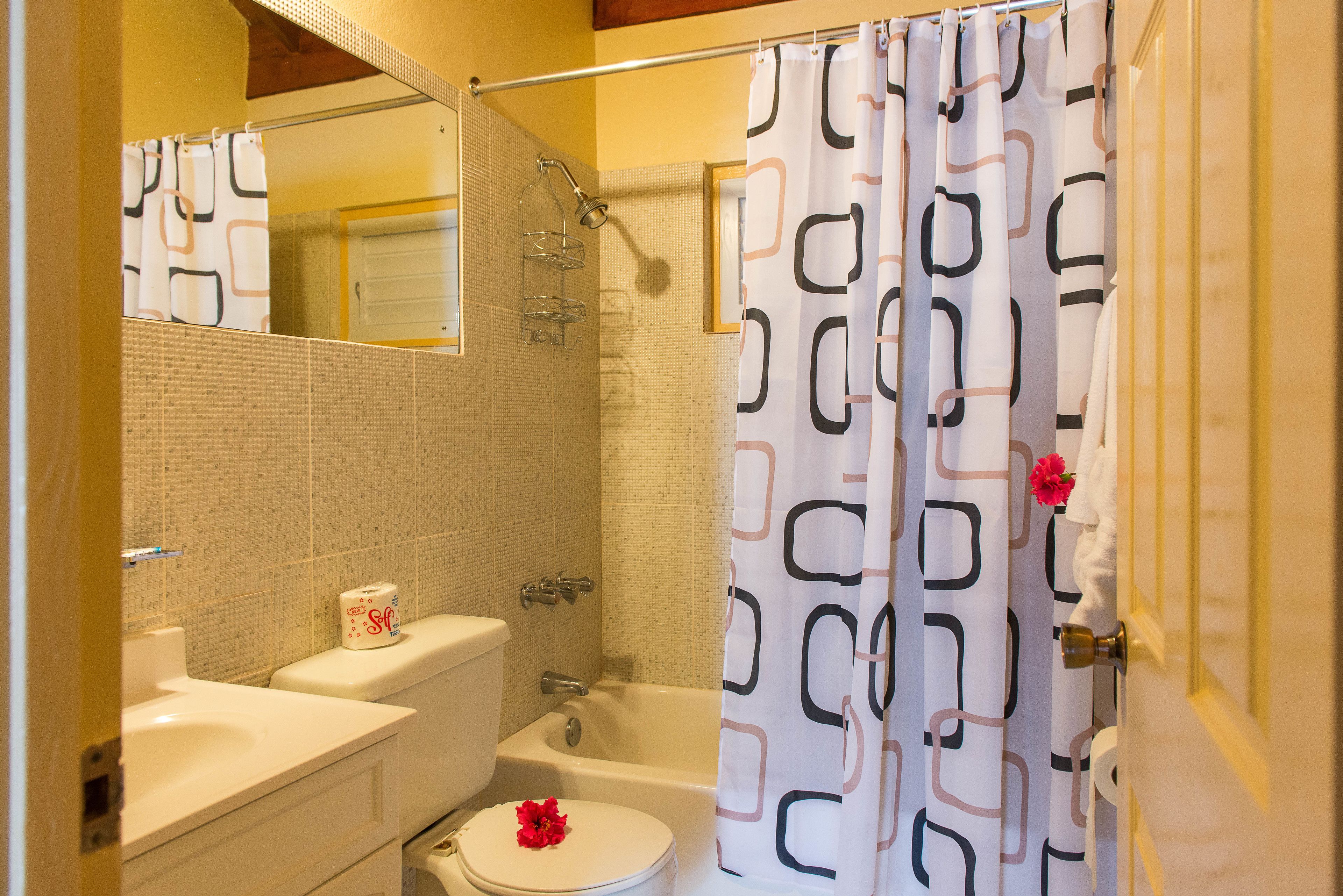 A bathroom with a toilet, sink, bathtub, and shower curtain.
