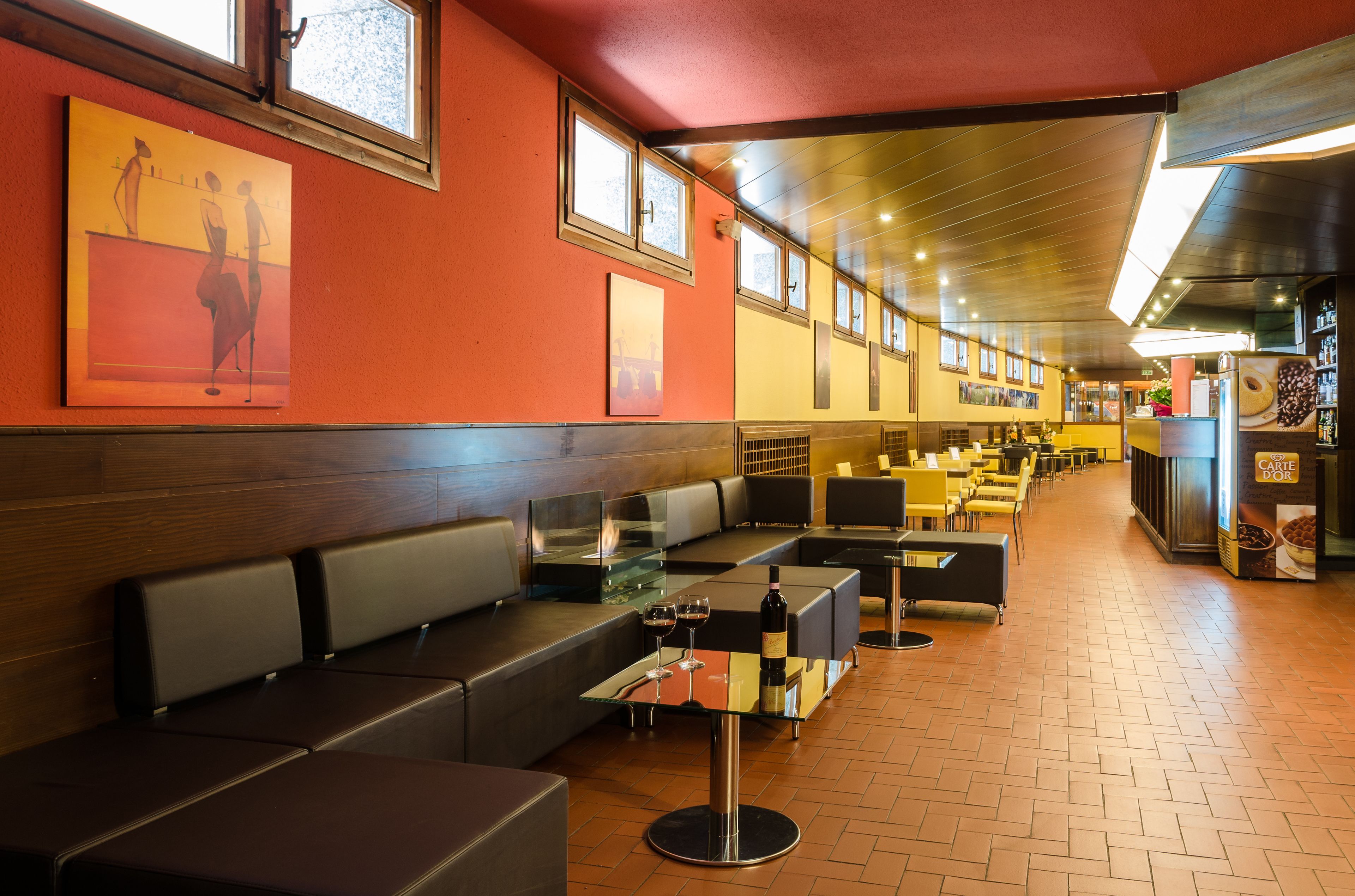 A restaurant with long communal tables, booths, and a bar area.