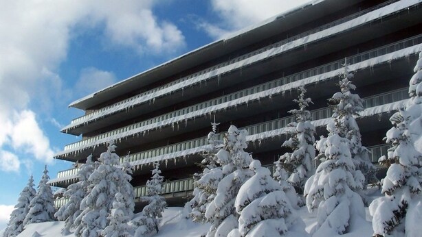 Un edificio de varios pisos con árboles cubiertos de nieve al frente.
