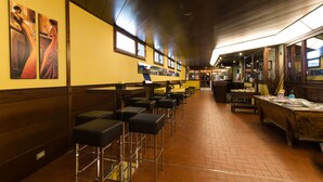 Un interior de restaurante con techos altos de madera, varias mesas y taburetes de bar, y obras de arte en las paredes.