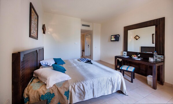 A hotel room with a bed, a desk, a chair, a mirror, and a television. - Welcome Meridiana Djerba (Djerba Midun)